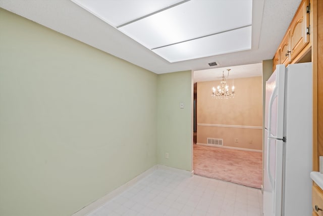 kitchen featuring a notable chandelier, white refrigerator, and hanging light fixtures