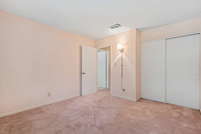 unfurnished bedroom with a closet and light colored carpet