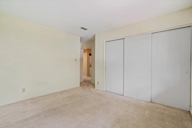 unfurnished bedroom featuring light colored carpet and a closet