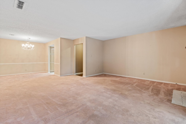 empty room with a textured ceiling, carpet flooring, and an inviting chandelier