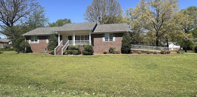 view of front of home with covered porch, a front yard, and brick siding