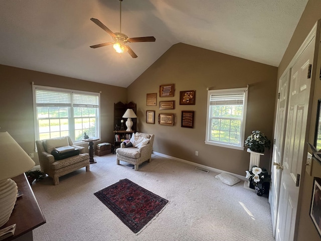 living area with vaulted ceiling, ceiling fan, light colored carpet, and plenty of natural light