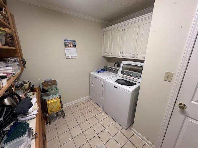 laundry area featuring light tile patterned flooring, washing machine and dryer, ornamental molding, and cabinets