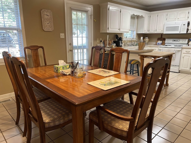 dining area with ornamental molding, light tile patterned floors, and plenty of natural light