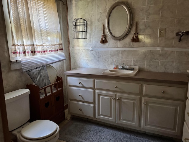 bathroom with vanity, tile walls, and toilet