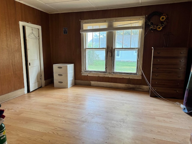 unfurnished bedroom with light wood-type flooring, multiple windows, and wooden walls