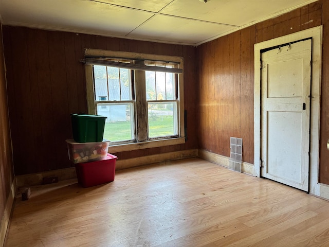 unfurnished room featuring wooden walls and light hardwood / wood-style flooring