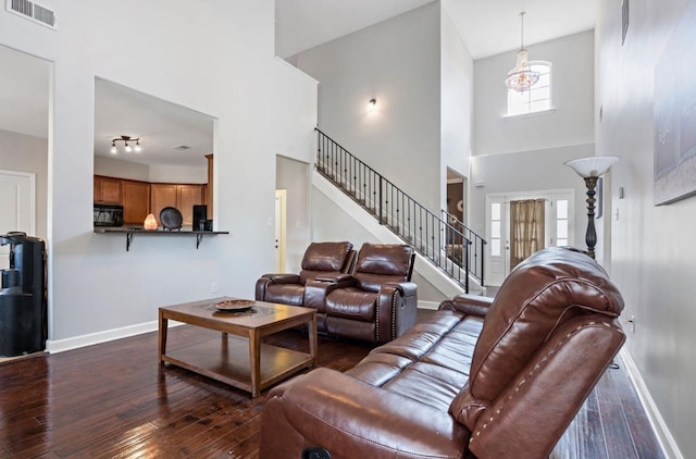 living room featuring high vaulted ceiling, a chandelier, and dark wood-type flooring