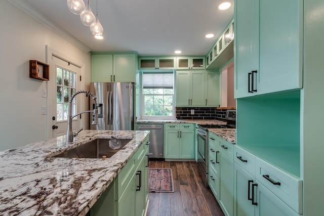 kitchen with light stone counters, green cabinetry, stainless steel appliances, crown molding, and dark hardwood / wood-style flooring