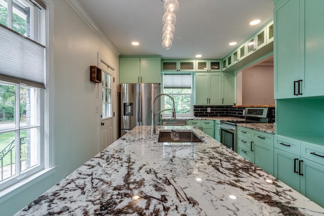 kitchen featuring light stone countertops, appliances with stainless steel finishes, green cabinets, and plenty of natural light