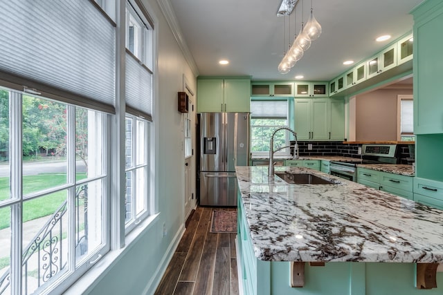 kitchen with light stone counters, green cabinetry, appliances with stainless steel finishes, and plenty of natural light