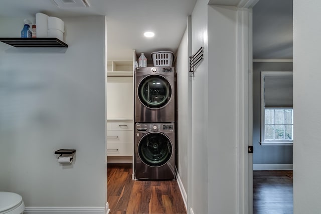 washroom featuring crown molding, dark hardwood / wood-style flooring, and stacked washing maching and dryer