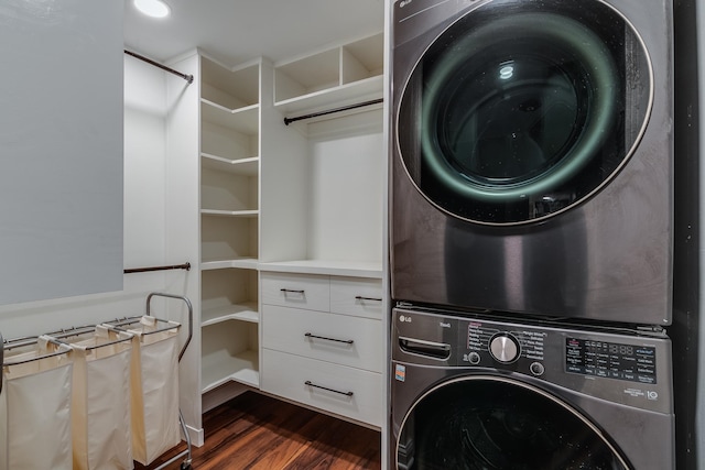 laundry area featuring stacked washer / drying machine and dark wood-type flooring