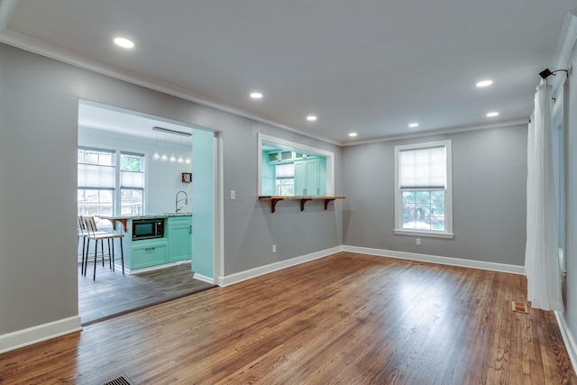 unfurnished room featuring wood-type flooring, plenty of natural light, and ornamental molding