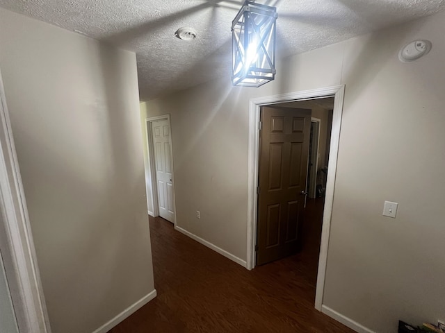 hallway with a textured ceiling and dark hardwood / wood-style floors