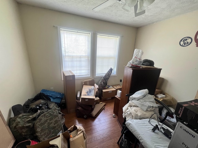 bedroom with a textured ceiling, ceiling fan, and dark wood-type flooring