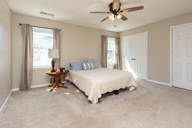 carpeted bedroom with multiple windows and ceiling fan