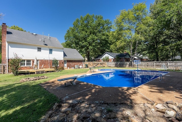 view of swimming pool with a lawn, a diving board, a deck, and a patio area