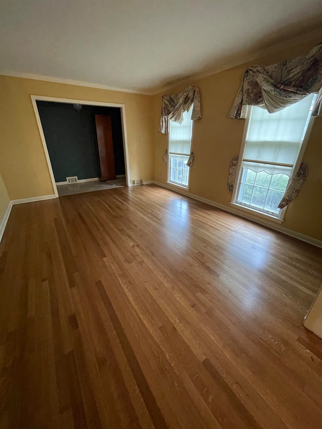 unfurnished living room with ornamental molding and hardwood / wood-style flooring