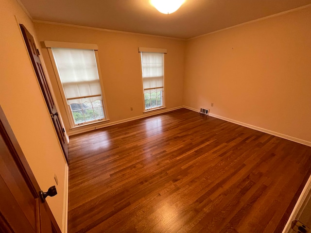 unfurnished room with ornamental molding and dark wood-type flooring