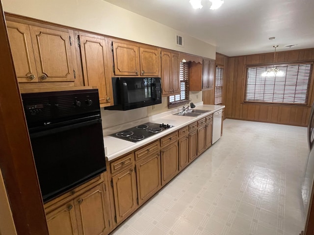 kitchen featuring hanging light fixtures, black appliances, sink, and a chandelier