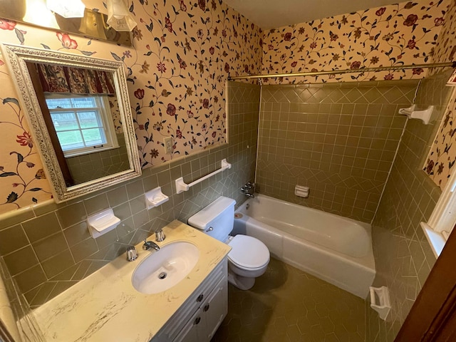 full bathroom with tile walls, vanity, toilet, and tiled shower / bath