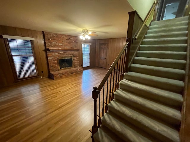 living room with hardwood / wood-style flooring, a fireplace, wooden walls, and a healthy amount of sunlight