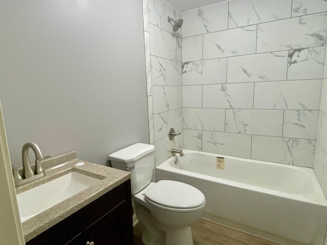 full bathroom with wood-type flooring, vanity, tiled shower / bath combo, and toilet