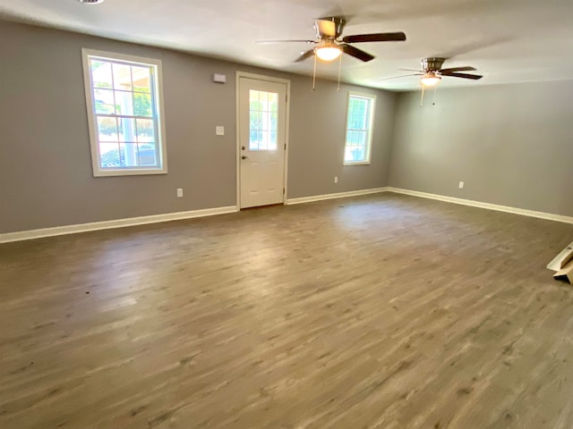 spare room with ceiling fan, plenty of natural light, and dark wood-type flooring