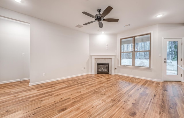 unfurnished living room featuring a tile fireplace, ceiling fan, and light hardwood / wood-style flooring