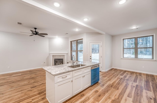 kitchen with sink, white cabinetry, light stone counters, a center island with sink, and stainless steel dishwasher