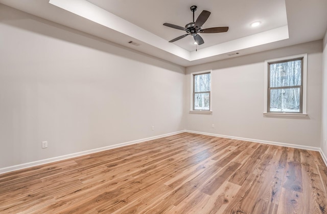 spare room featuring ceiling fan, a raised ceiling, and light hardwood / wood-style flooring