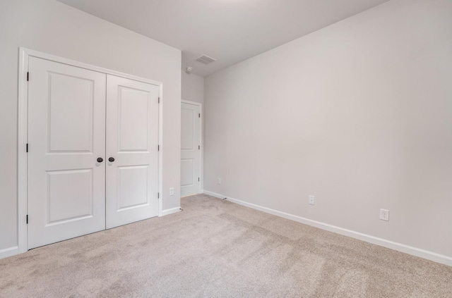 unfurnished bedroom featuring light colored carpet and a closet