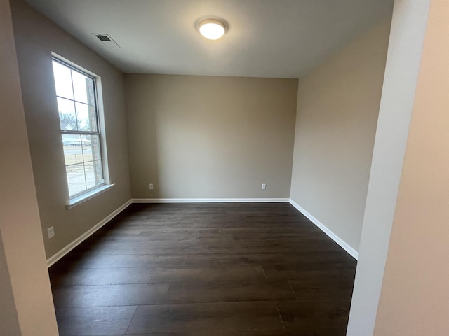 empty room with visible vents, baseboards, and dark wood-style flooring