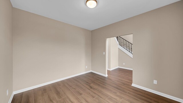 spare room with stairway, baseboards, and wood finished floors