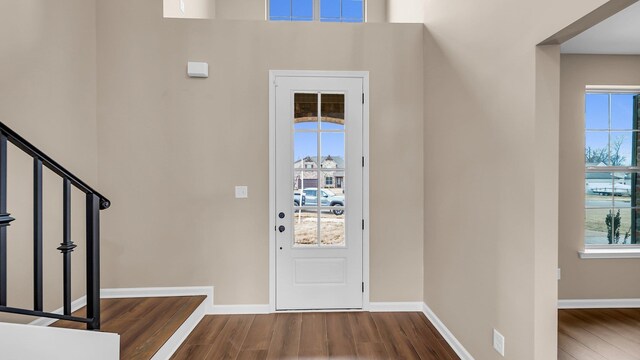 entryway with dark wood-style floors, plenty of natural light, and stairs