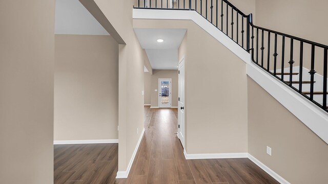 hall with dark wood-style floors, a high ceiling, and baseboards