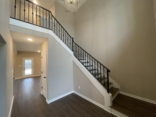 stairway featuring a high ceiling, baseboards, and wood finished floors