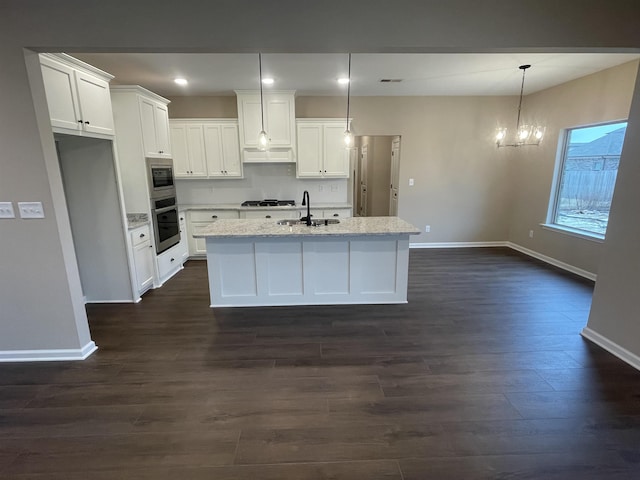 kitchen featuring stainless steel appliances, a sink, white cabinets, a center island with sink, and pendant lighting