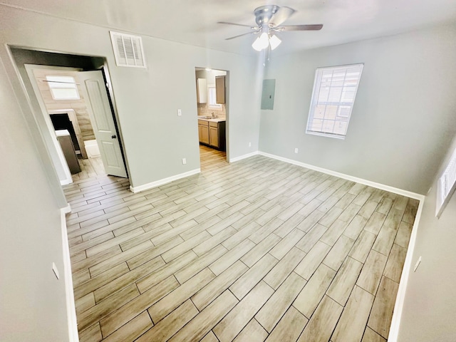 unfurnished bedroom with ceiling fan, electric panel, sink, light hardwood / wood-style flooring, and ensuite bath