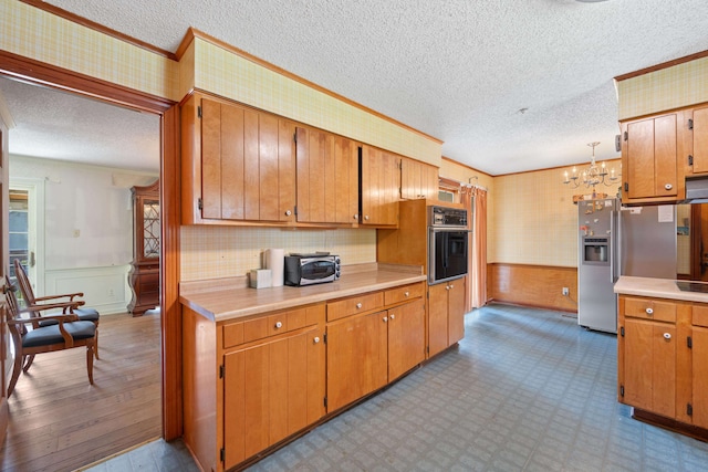 kitchen featuring tasteful backsplash, light wood-type flooring, a textured ceiling, oven, and a chandelier