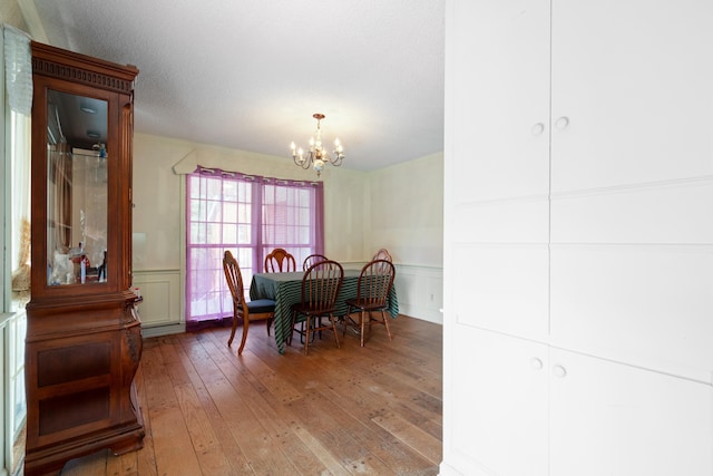 dining room with a textured ceiling, hardwood / wood-style floors, and a notable chandelier