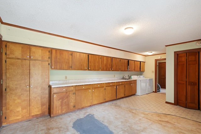 kitchen with a textured ceiling, washer and clothes dryer, crown molding, and sink