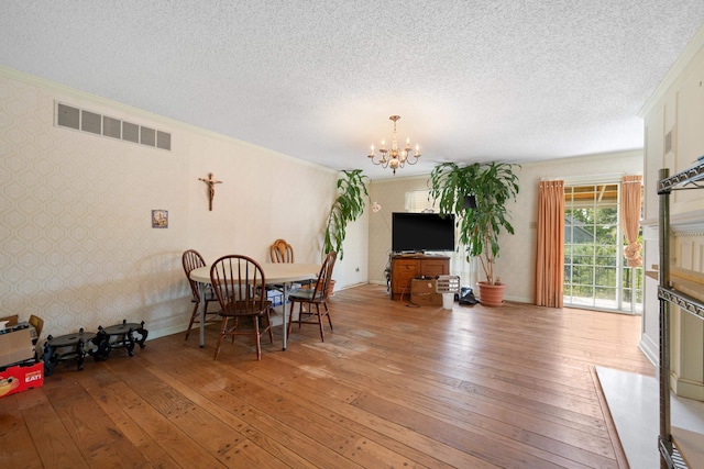 dining space with a chandelier, a textured ceiling, and hardwood / wood-style floors