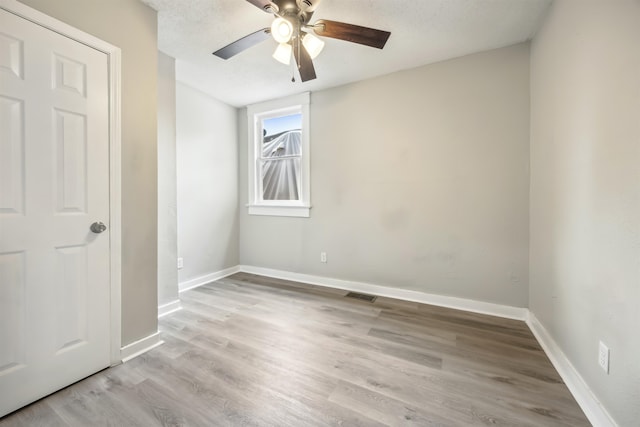 unfurnished room featuring light wood-type flooring, ceiling fan, and a textured ceiling