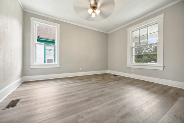 spare room with ornamental molding, wood-type flooring, ceiling fan, and a healthy amount of sunlight