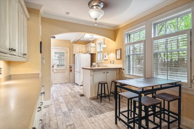 dining space with light wood-type flooring and ornamental molding