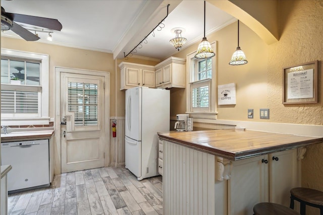 kitchen with ornamental molding, white appliances, decorative light fixtures, a kitchen breakfast bar, and wood counters