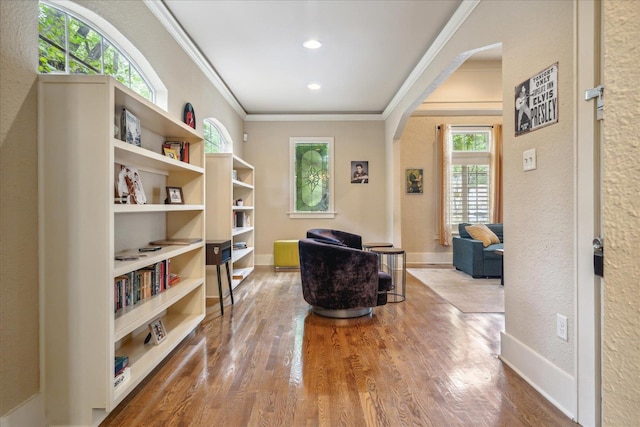 sitting room with wood-type flooring, plenty of natural light, and crown molding