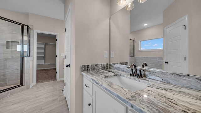 bathroom with a shower with door and vanity